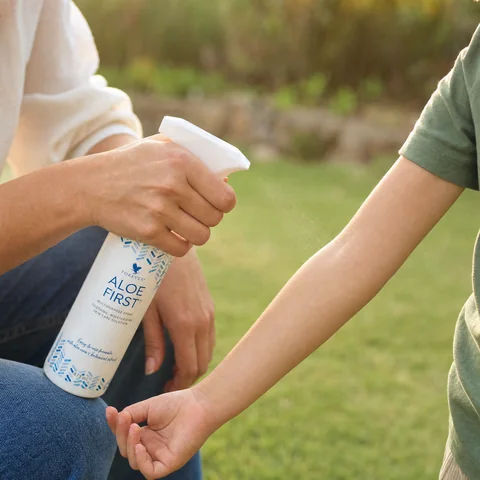 Aloe First pulverizat pe brațul unui copil, în grădină, după joacă